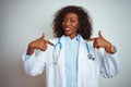 Young african american doctor woman wearing stethoscope over isolated white background looking confident with smile on face, Royalty Free Stock Photo