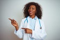 Young african american doctor woman wearing stethoscope over isolated white background smiling and looking at the camera pointing Royalty Free Stock Photo