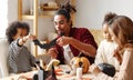 Young african american family sitting at table and preparing Halloween decorations at home