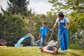 Young african american father mowing grass outdoors with his young son. Working together in the backyard Royalty Free Stock Photo