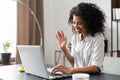 African American woman typing an email and waving