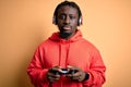 Young african american gamer man playing video game using joystick and headphones with a confident expression on smart face Royalty Free Stock Photo