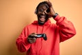Young african american gamer man playing video game using joystick and headphones with happy face smiling doing ok sign with hand Royalty Free Stock Photo