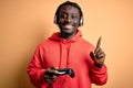 Young african american gamer man playing video game using joystick and headphones surprised with an idea or question pointing Royalty Free Stock Photo