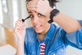 Young african american girl applying eyelashes mascara stressed with hand on head, shocked with shame and surprise face, angry and Royalty Free Stock Photo