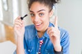 Young african american girl applying eyelashes mascara surprised with an idea or question pointing finger with happy face, number Royalty Free Stock Photo