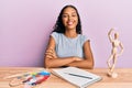 Young african american girl artist sitting at studio table happy face smiling with crossed arms looking at the camera Royalty Free Stock Photo