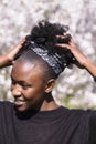 Young african girl in blossom park fixes hairstyle Royalty Free Stock Photo