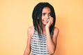 Young african american girl child with braids over yellow background looking stressed and nervous with hands on mouth biting nails