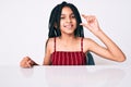 Young african american girl child with braids wearing casual clothes sitting on the table smiling and confident gesturing with Royalty Free Stock Photo