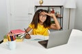 Young african american girl doing homework at home very happy and smiling looking far away with hand over head Royalty Free Stock Photo