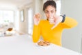 Young african american girl eating chocolate chips cookies as sweet snack with angry face, negative sign showing dislike with Royalty Free Stock Photo