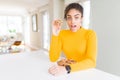 Young african american girl eating chocolate chips cookies as sweet snack scared in shock with a surprise face, afraid and excited Royalty Free Stock Photo