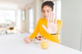 Young african american girl eating healthy cereals for breakfast with open hand doing stop sign with serious and confident