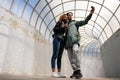 A young African-American girl and a European guy make a salfi with a small action camera. People inside the pedestrian crossing wi Royalty Free Stock Photo