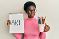 Young african american girl holding art notebook and colored pencils smiling looking to the side and staring away thinking Royalty Free Stock Photo