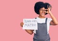 Young african american girl holding black lives matter banner smiling happy doing ok sign with hand on eye looking through fingers