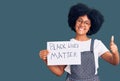 Young african american girl holding black lives matter banner smiling happy and positive, thumb up doing excellent and approval