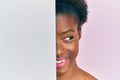 Young african american girl holding blank empty banner over half face smiling looking to the side and staring away thinking Royalty Free Stock Photo