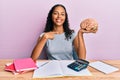 Young african american girl holding brain studying for school pointing finger to one self smiling happy and proud