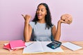 Young african american girl holding brain studying for school pointing thumb up to the side smiling happy with open mouth