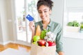 Young african american girl holding paper bag of groceries and credit card as payment with a happy face standing and smiling with Royalty Free Stock Photo