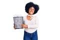 Young african american girl holding paper bin full of crumpled papers looking positive and happy standing and smiling with a Royalty Free Stock Photo