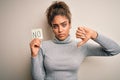 Young african american girl holding reminder paper with no word negative message with angry face, negative sign showing dislike