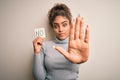 Young african american girl holding reminder paper with no word negative message with open hand doing stop sign with serious and