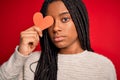 Young african american girl holding romantic heart paper shape over red isolated background with a confident expression on smart