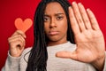 Young african american girl holding romantic heart paper shape over red isolated background with open hand doing stop sign with Royalty Free Stock Photo