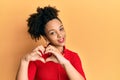 Young african american girl listening to music using headphones smiling in love showing heart symbol and shape with hands Royalty Free Stock Photo