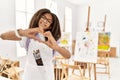 Young african american girl painting at art studio smiling in love showing heart symbol and shape with hands Royalty Free Stock Photo