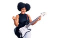 Young african american girl playing electric guitar screaming proud, celebrating victory and success very excited with raised arms Royalty Free Stock Photo