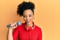 Young african american girl singing song using microphone and headphones looking positive and happy standing and smiling with a Royalty Free Stock Photo