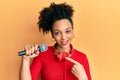 Young african american girl singing song using microphone and headphones smiling happy pointing with hand and finger Royalty Free Stock Photo