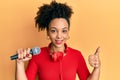Young african american girl singing song using microphone and headphones smiling happy and positive, thumb up doing excellent and Royalty Free Stock Photo
