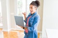 Young african american girl standing working using laptop pointing and showing with thumb up to the side with happy face smiling Royalty Free Stock Photo