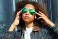 Young african american girl in sunglasses, posing outdoors, Dressed casual, with short voluminous hair. Royalty Free Stock Photo