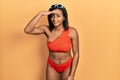 Young african american girl wearing bikini very happy and smiling looking far away with hand over head Royalty Free Stock Photo