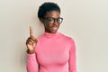 Young african american girl wearing casual clothes and glasses smiling with an idea or question pointing finger up with happy Royalty Free Stock Photo