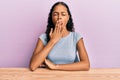 Young african american girl wearing casual clothes sitting on the table bored yawning tired covering mouth with hand Royalty Free Stock Photo