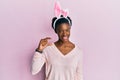 Young african american girl wearing cute easter bunny ears smiling and confident gesturing with hand doing small size sign with Royalty Free Stock Photo