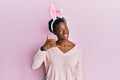 Young african american girl wearing cute easter bunny ears smiling doing phone gesture with hand and fingers like talking on the Royalty Free Stock Photo