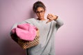 Young african american girl wearing glasses doing housework holding wicker basket with clothes with angry face, negative sign