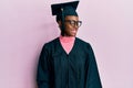 Young african american girl wearing graduation cap and ceremony robe smiling looking to the side and staring away thinking Royalty Free Stock Photo