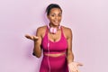 Young african american girl wearing gym clothes and using headphones smiling cheerful with open arms as friendly welcome, positive Royalty Free Stock Photo