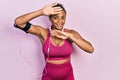 Young african american girl wearing gym clothes and using headphones smiling cheerful playing peek a boo with hands showing face Royalty Free Stock Photo