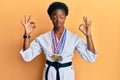 Young african american girl wearing karate kimono and black belt relax and smiling with eyes closed doing meditation gesture with Royalty Free Stock Photo