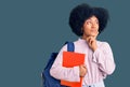 Young african american girl wearing student backpack holding book serious face thinking about question with hand on chin, Royalty Free Stock Photo